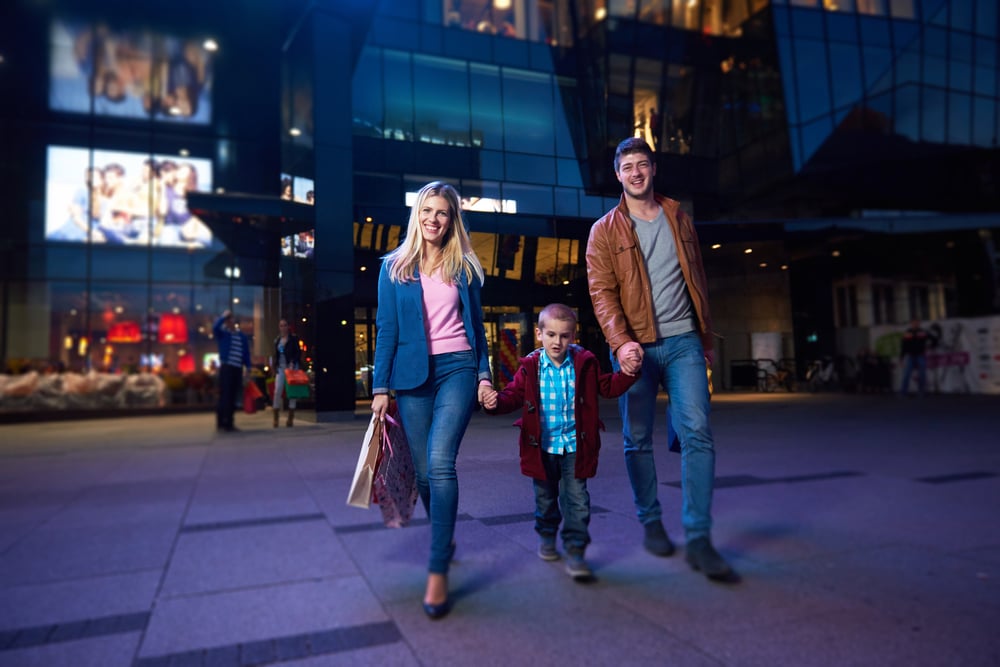 happy family walking with paper bag in front of  shopping mall