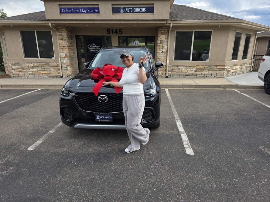 A happy client holding up her keys in front of her new Mazda at RH Auto Brokers in Colorado Springs