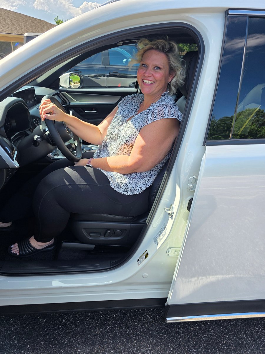 A client smiling in the driver's seat of her new car